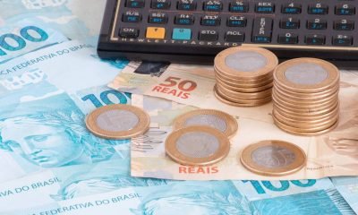 finance-concept-one-hundred-reais-bills-coins-with-calculator-pen-brazilian-money-scaled-1.jpg